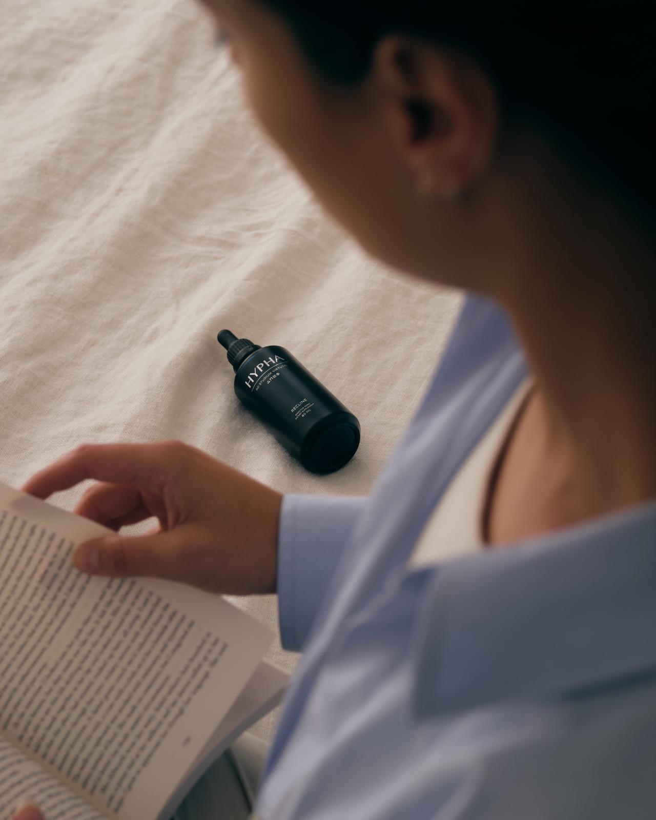 Reading in bed, a bottle of Recline beside her